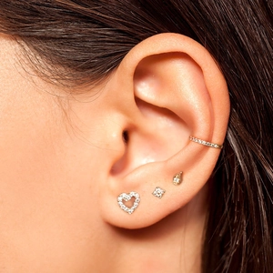 Macro shot of S925 sterling silver ear piercings featuring zircon heart and clover studs