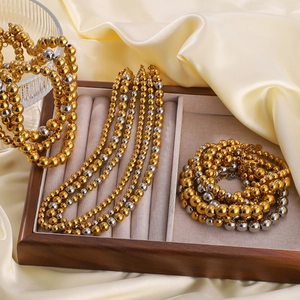 Polished 18K gold and silver bead necklace and bracelet set on a luxury velvet display