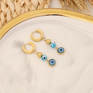 Gold evil eye hoop earrings with blue bead accents on white marble display