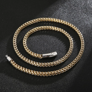 Detail of two-tone gold and silver wheat chain necklace with intricate braided metal texture