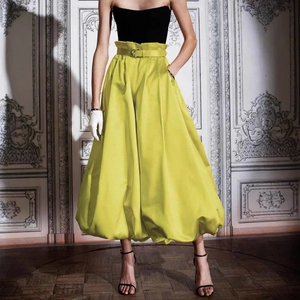 Détail d'une jupe bouffante jaune à taille haute avec finition satinée et large ceinture