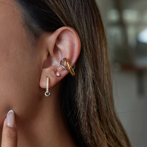 Close-up of two-tone gold and silver earrings with white diamond stud on ear model