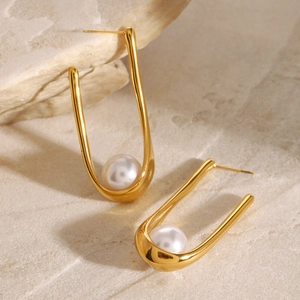 Modern U-shaped gold stainless steel earrings with white pearl detail on natural stone