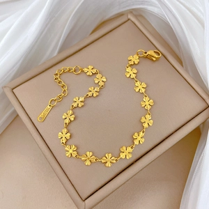 Elegant gold titanium steel clover chain bracelet displayed on soft white silk fabric