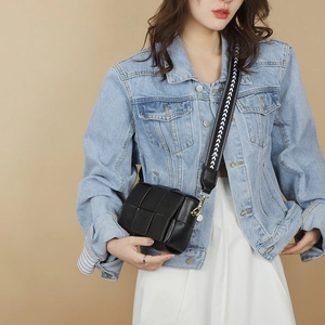 Detail of black woven leather crossbody bag with textured wide shoulder strap