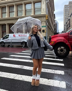 Street style view of a gray wool jacket and pleated skirt worn in rainy New York City