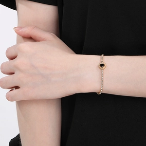 Elegant gold heart bracelet with black enamel and zircon crystals on female wrist