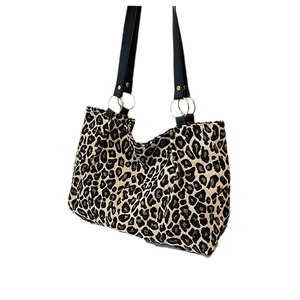 Leopard print canvas tote bag with black leather handles and metal ring hardware