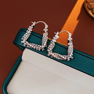 Macro shot of silver U-shaped earrings with zircon pave on a vintage green jewelry box