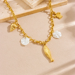 Gold charm necklace featuring seashell, fish and shell pendants on textured background