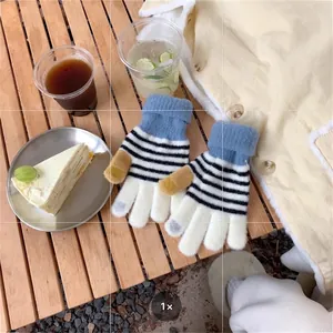Detail of warm striped knit gloves with touchscreen fingers on a wooden surface