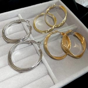 Vue détaillée des boucles d'oreilles créoles texturées en or 18k et argent sur velours