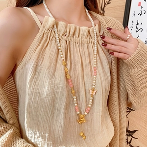 Long faux pearl necklace with golden butterfly and floral tassel on an elegant model