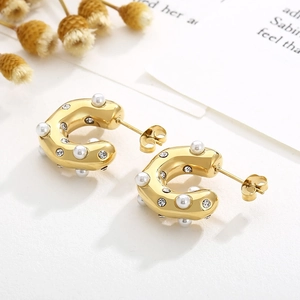 Detail of C-shaped 18K gold earrings featuring inlaid white pearls and clear zircons