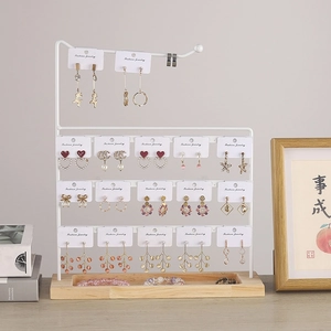 Three-tier white metal earring display stand with a solid wood storage base