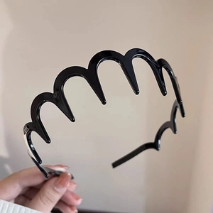Détail d'un serre-tête noir ondulé en plastique montrant la texture et la forme