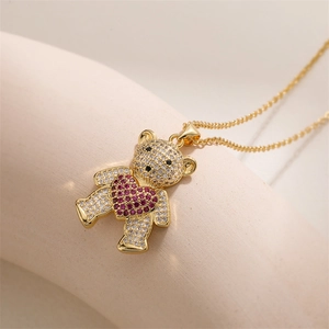 Détail d'un pendentif ours doré avec zircons blancs et un cœur en cristal rose brillant