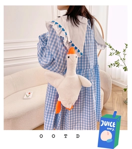 Detail of cute goose plush bag with blue heart strap shown on model outfit