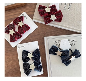 Detail of velvet bow hair clips with glittering stars in burgundy and navy blue