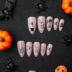 Faux ongles Halloween roses avec motifs de crâne noir et pointes à paillettes