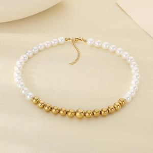 Close-up of pearl and gold bead necklace with lobster clasp on beige textured background