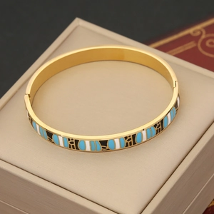 Retro gold stainless steel bangle with blue and white enamel eye patterns on a jewelry box