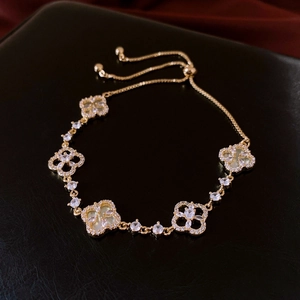 Detail of clover bracelet with white shell inlay and gold finish on black leather