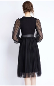Back view of a black knitted dress featuring sheer polka dot sleeves and a pleated mesh hem