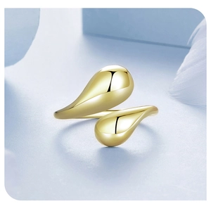 Polished golden teardrop open ring with high gloss metallic finish on blue background