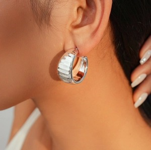 Close-up of a silver-tone hammered wide C-shape hoop earring worn by a female model