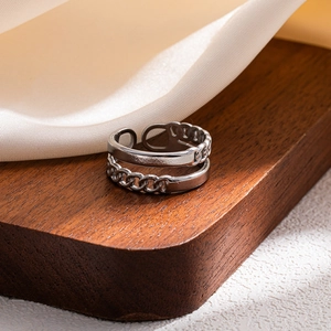 Detail of silver stackable ring with smooth surface and chain texture on wood background