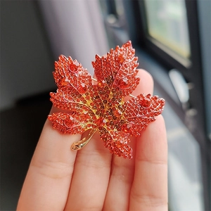 Close-up of maple leaf brooch with orange crystal rhinestones and golden alloy base