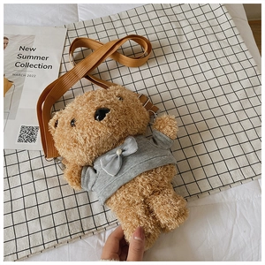 Detail of cute brown plush teddy bear crossbody bag with pearl bow and woven strap