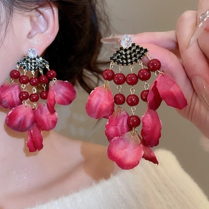 Close-up of vintage petal tassel earrings with red beads and floral fabric details