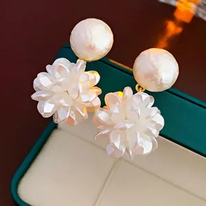 Exquisite white flower pearl earrings with gold accents on a dark green jewelry box