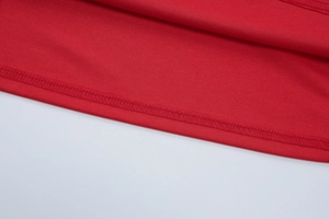 Gros plan des coutures de haute qualité sur l'ourlet d'une robe rouge en maille ajustée