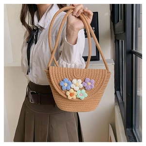 Detail of handmade woven straw bucket bag with colorful crochet floral decorations