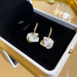 Detailed view of white camellia drop earrings with gold plating and cubic zirconia