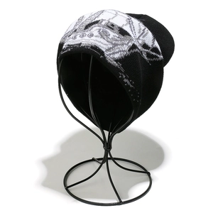 Détail d'un bonnet en tricot noir avec motif artistique blanc sur un support en métal