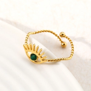 Detailed macro view of golden evil eye ring with green stone and twisted rope band texture