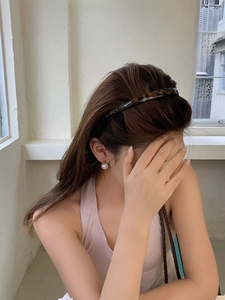 Close-up of stylish tortoiseshell headband and pearl earrings worn by a female model