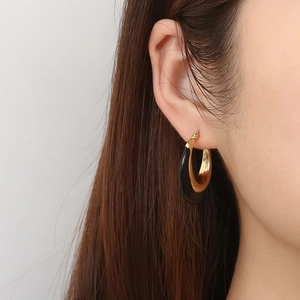 Vintage gold hoop earrings with black enamel inlay worn by a model for a stylish look