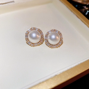 Macro shot of gold-plated pearl stud earrings with zircon halo and vintage French style
