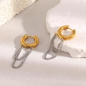 Detail of two-tone chain tassel earrings in 18K gold and silver on a white textured surface