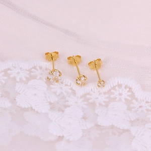 Detailed view of three gold-plated S925 sterling silver star earrings on white lace fabric