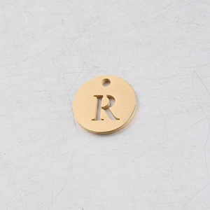 Détail d'un pendentif rond doré en acier de 12 mm avec la lettre R évidée gravée