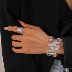 Macro detail of silver leaf-shaped bracelet and ring set with textured vein patterns