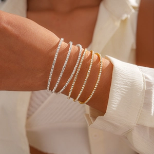 Close-up of five layered tennis bracelets with shimmering zircons in gold and silver