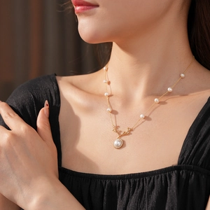 Dettaglio della collana con ciondolo a corno di cervo dorato con perle e zirconi