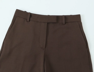 Detail of deep brown woven trousers waist with belt loops and clean stitching